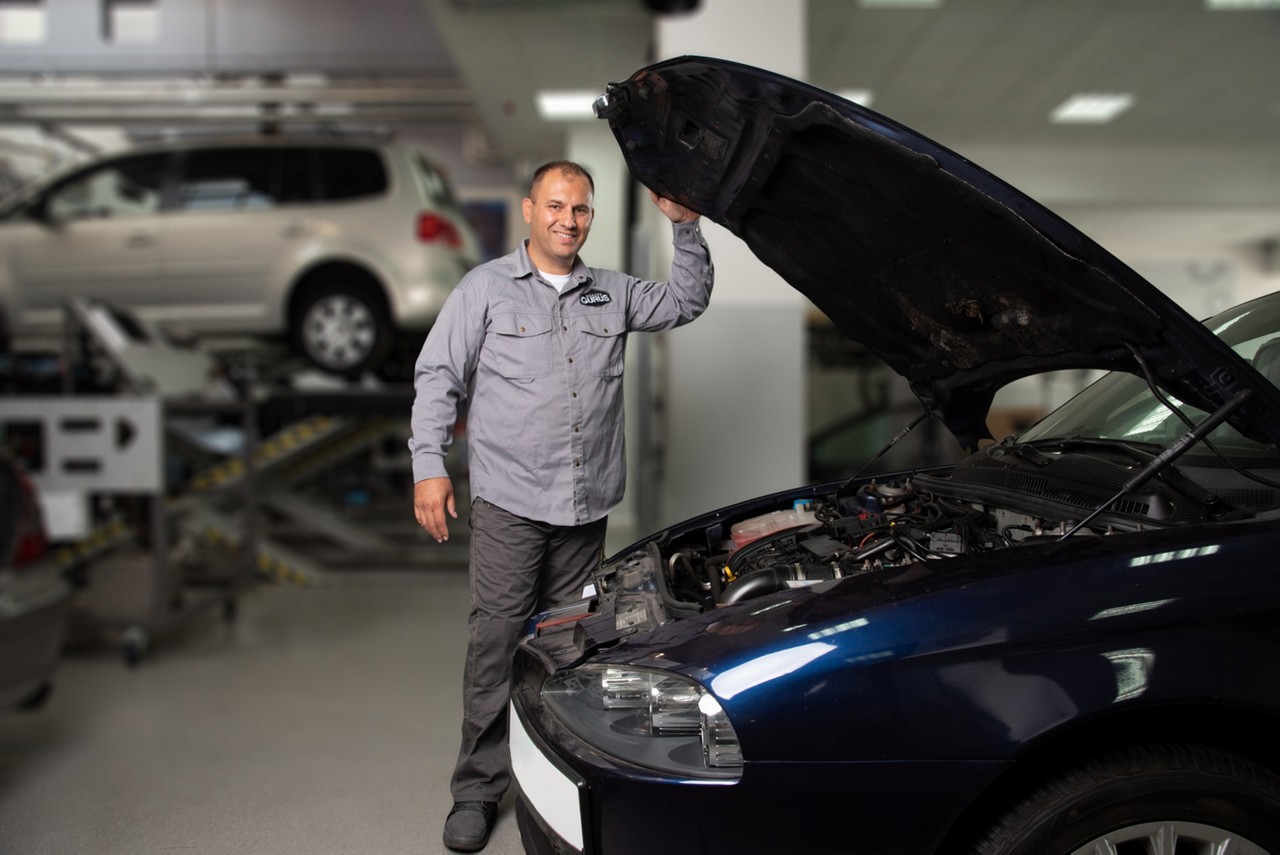 Garage Gurus in einer Werkstatt, eine Motorhaube geöffnet haltend